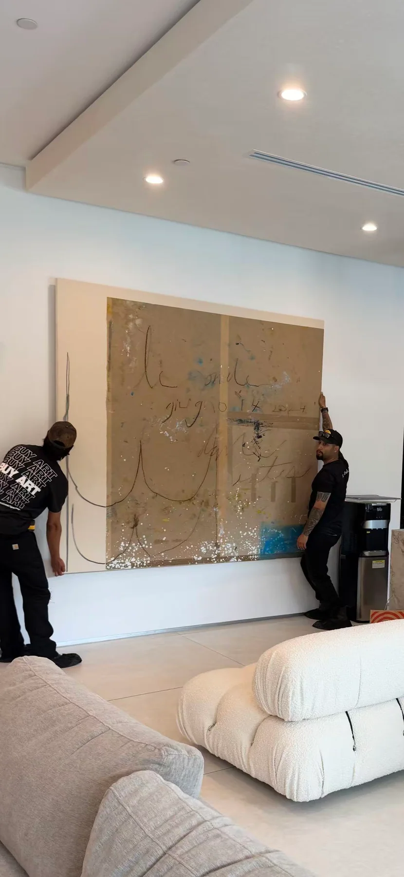 Professional installers positioning a large abstract artwork in a Beverly Hills residence