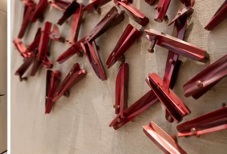 Close-up showing the red sculptural wall art materials and mounting details